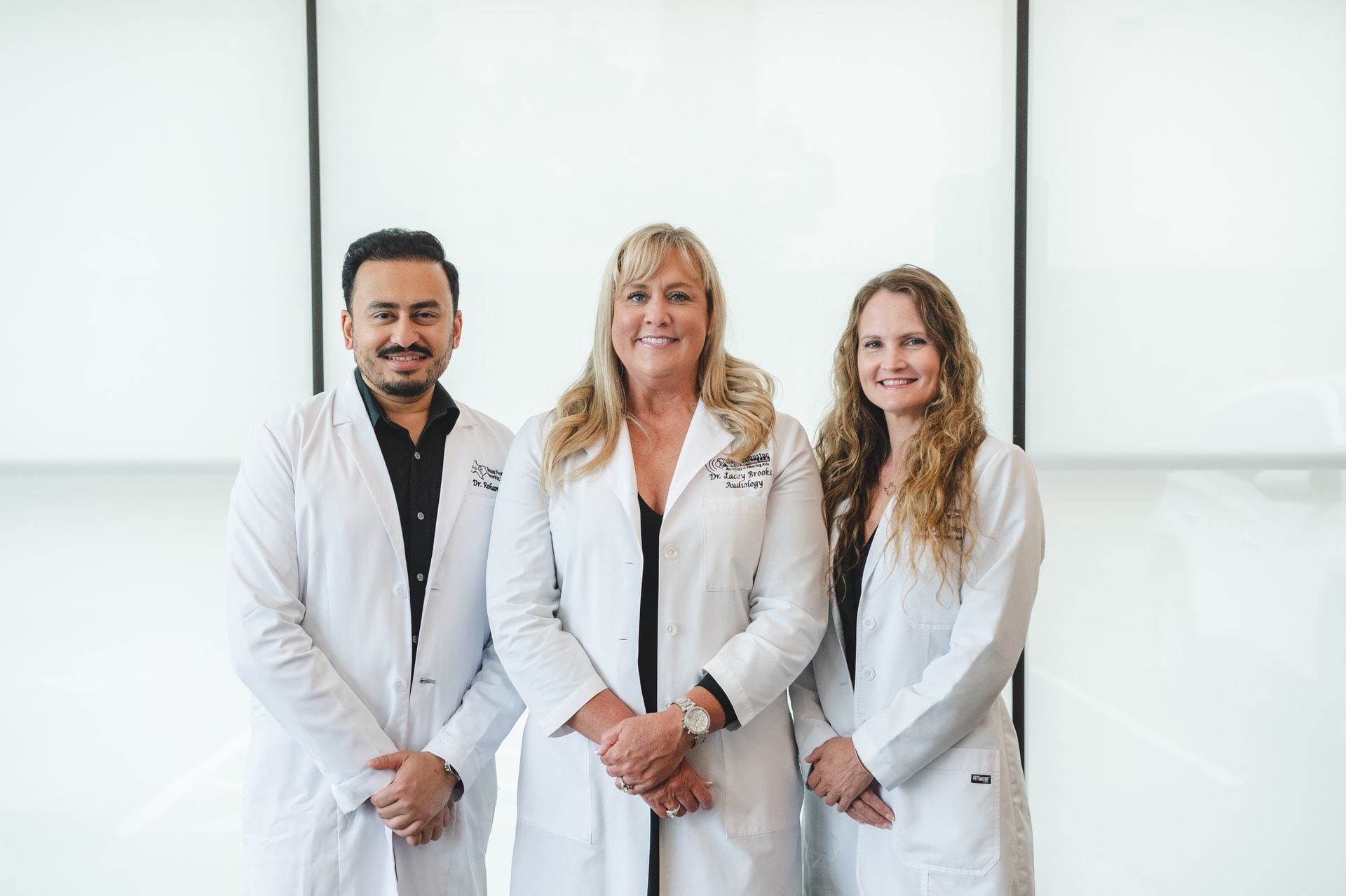 Three doctors in white coats are posing for a picture.