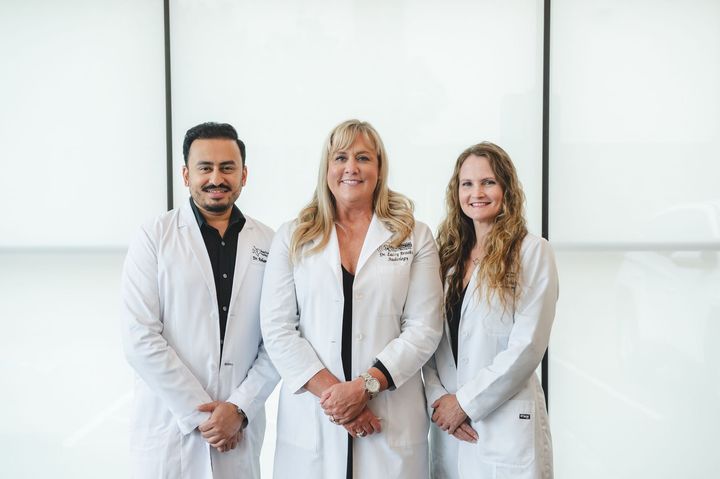 Three doctors in white coats are posing for a picture.