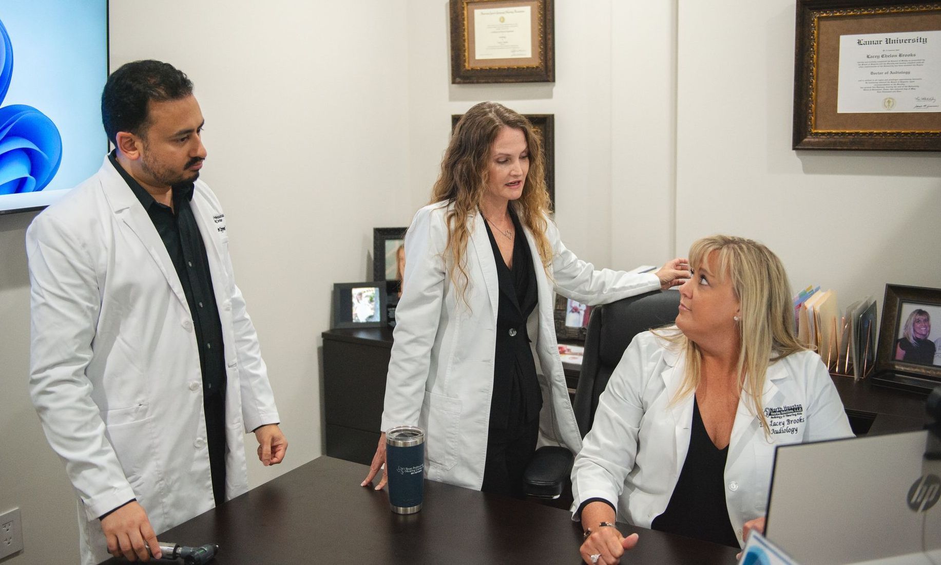 A group of doctors are standing around a table in an office.