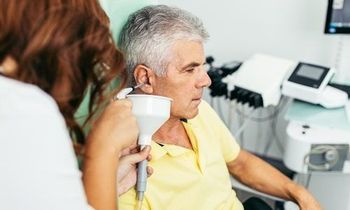 An elderly man is being examined by a nurse in a hospital.