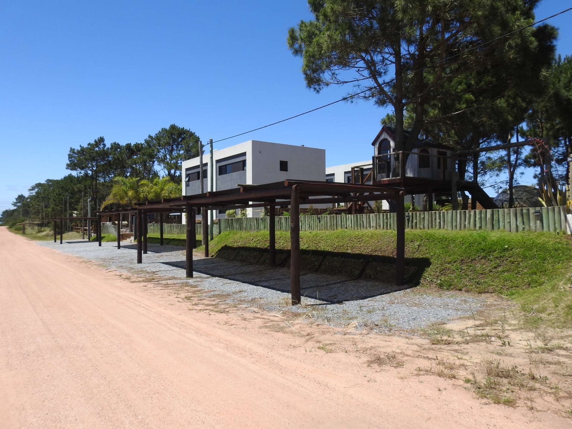 A row of wooden structures along the side of a dirt road