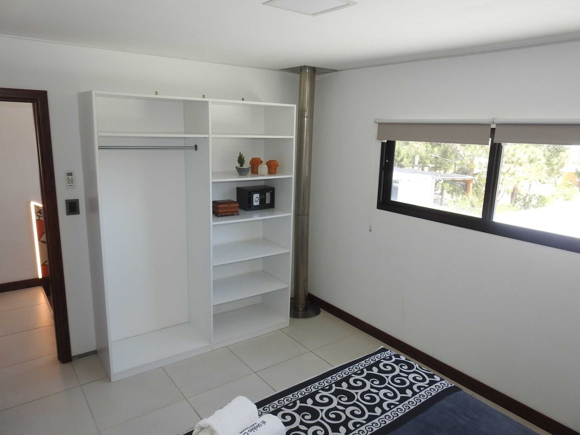 A bedroom with a bed , shelves , and a window.