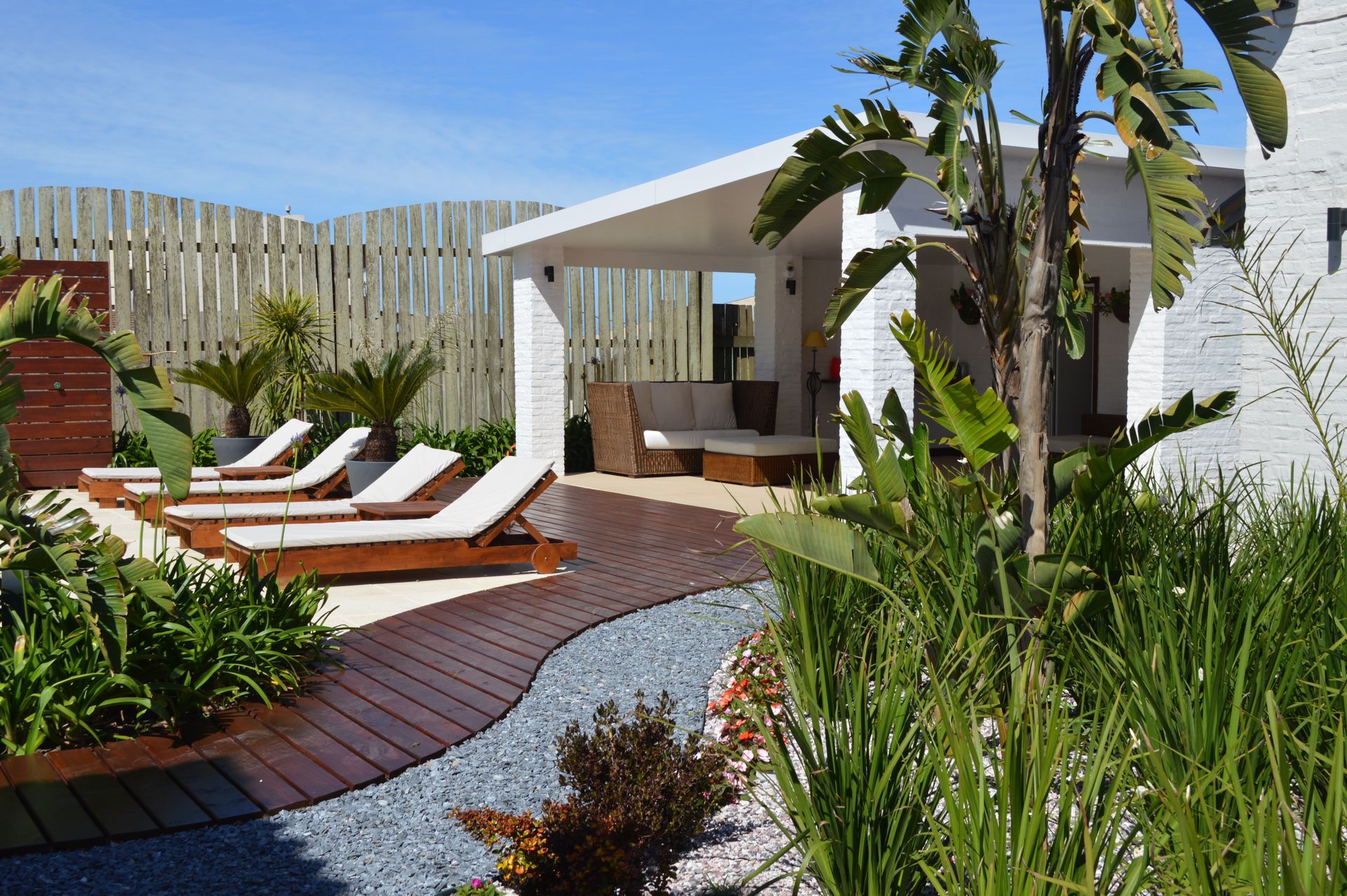 A white house with a wooden deck and lawn chairs in front of it