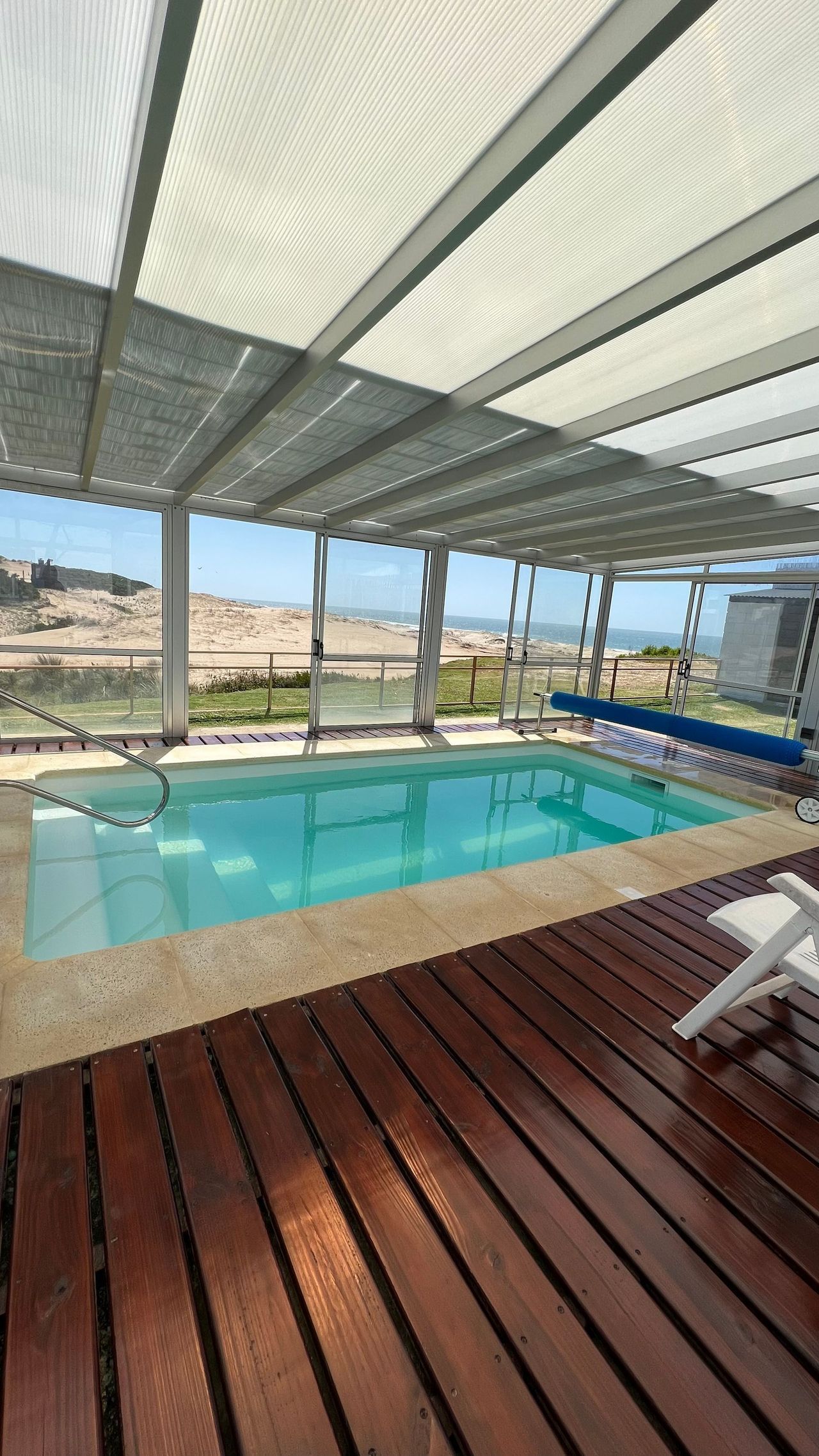 A large indoor swimming pool with a wooden deck in front of it