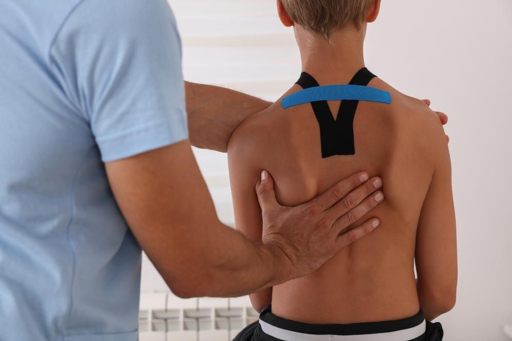 A Young Boy With Kinesio Tape On His Back — Mark Coulton Cardiff Physiotherapy Centre In Cardiff, NSW