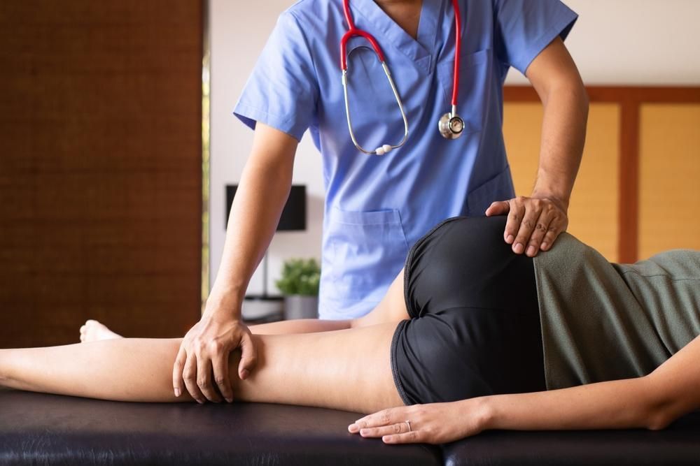 A Doctor Is Examining A Patient 's Leg On A Table — Mark Coulton Cardiff Physiotherapy Centre In Newcastle, NSW