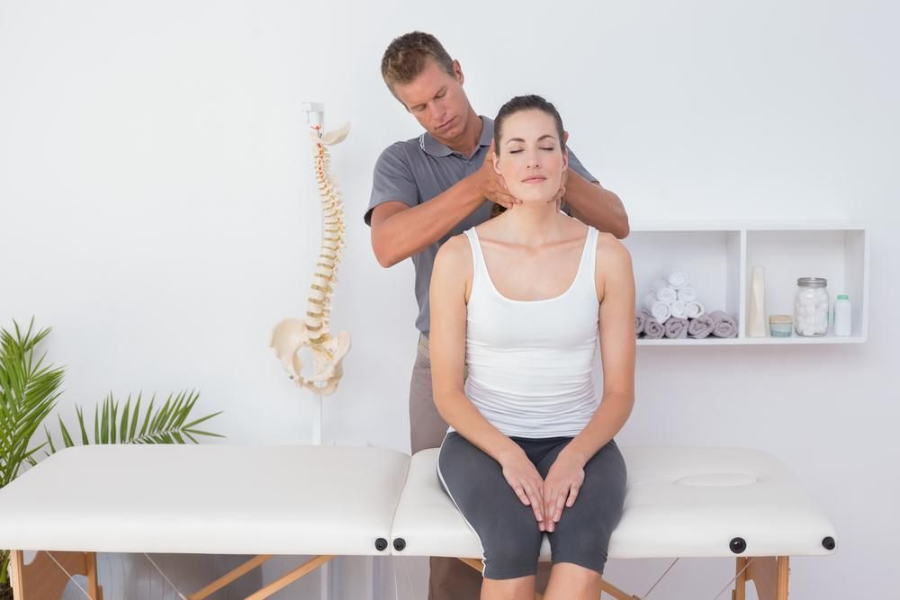 A Woman Is Sitting On A Table Getting A Neck Massage — Mark Coulton Cardiff Physiotherapy Centre In Cameron Park, NSW