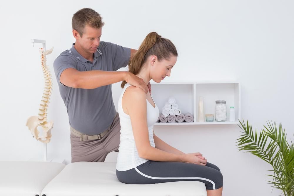 A Man Is Giving A Woman A Massage On Her Neck — Mark Coulton Cardiff Physiotherapy Centre In Cardiff, NSW