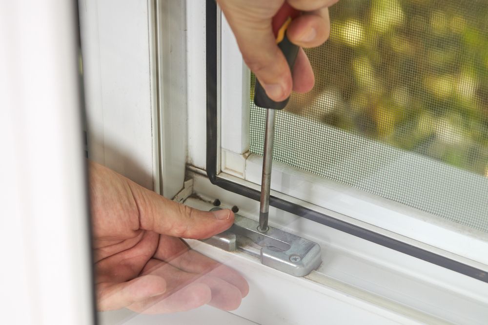 Person Uses a Screwdriver to Tighten a Metal Latch — Suburban Security Screens in Currumbin, QLD