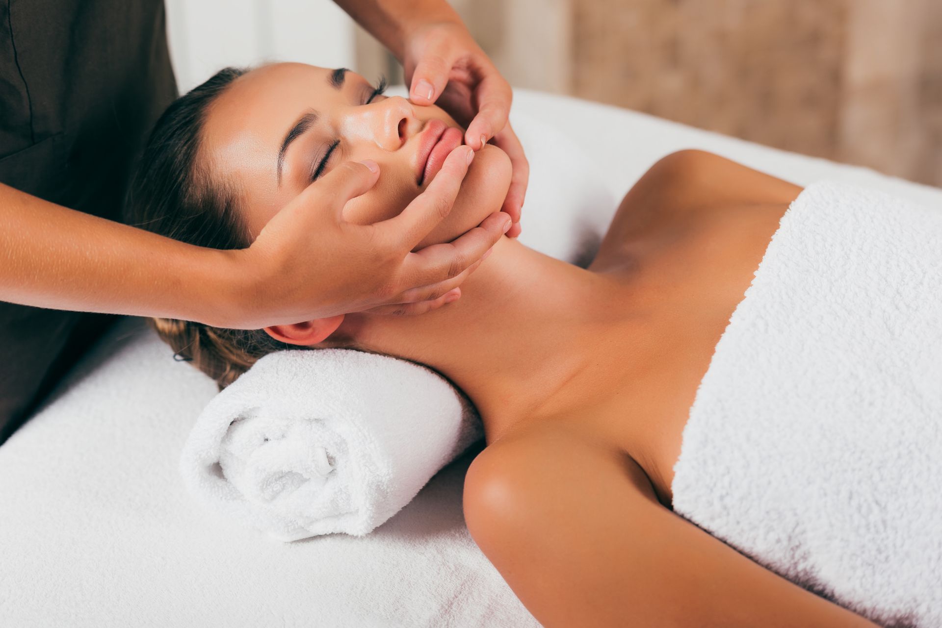 A woman is getting a facial massage at a spa.