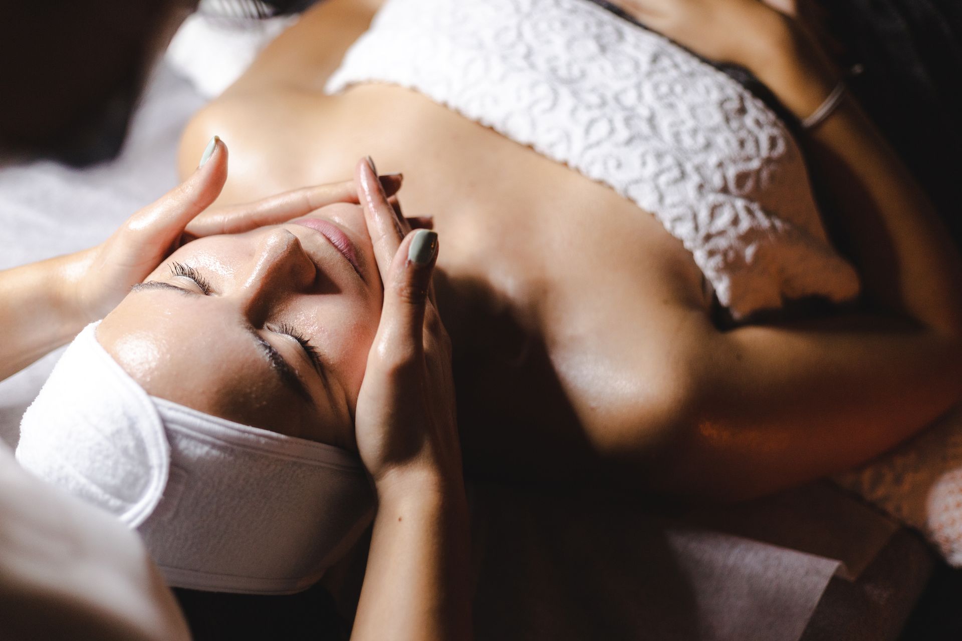 A woman is getting a facial massage at a spa.