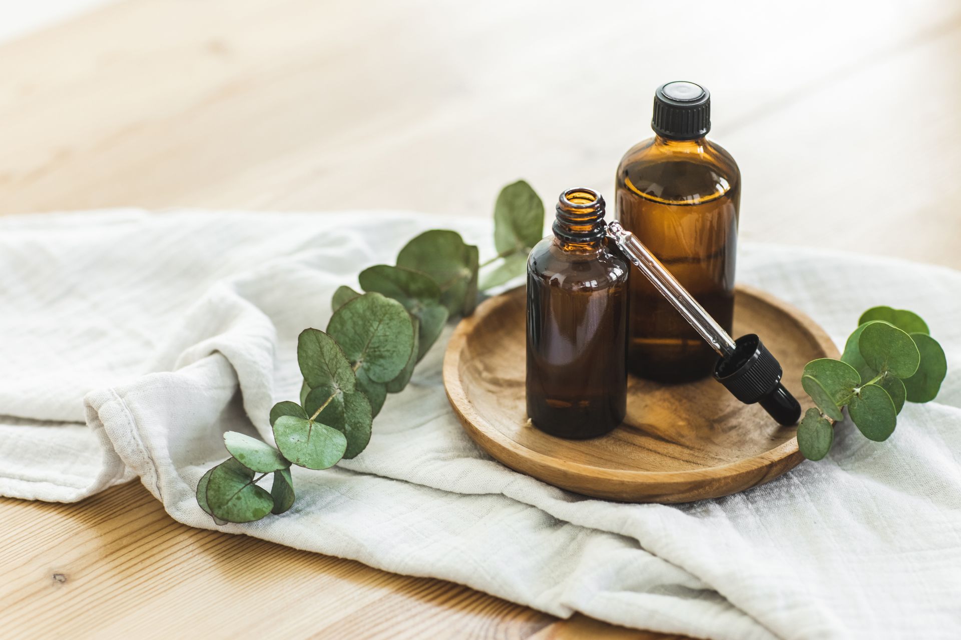 Two bottles of essential oil with a pipette on a wooden tray.