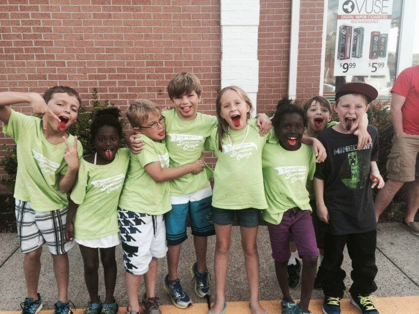 A group of children wearing green shirts are posing for a picture