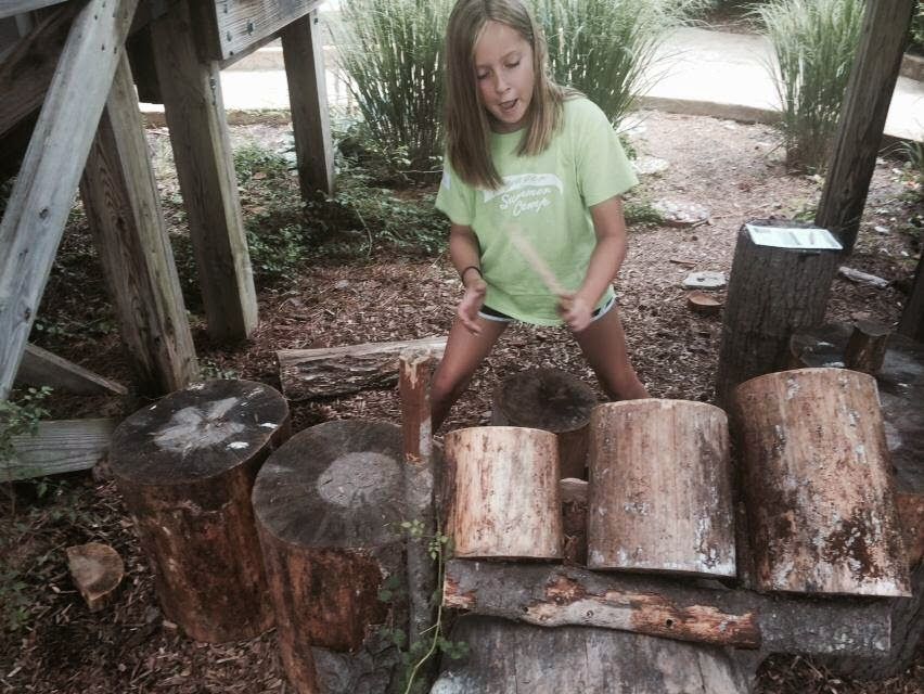 A little girl in a green shirt is playing with logs