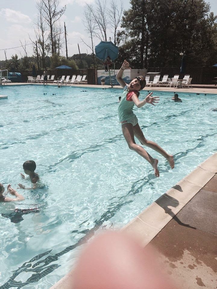 A girl is jumping into a swimming pool.