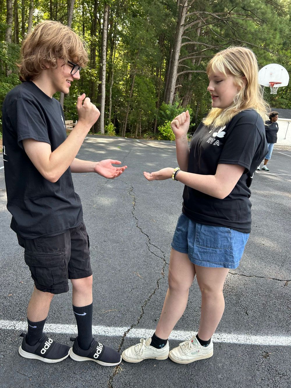 A boy and a girl are standing next to each other on the side of the road.