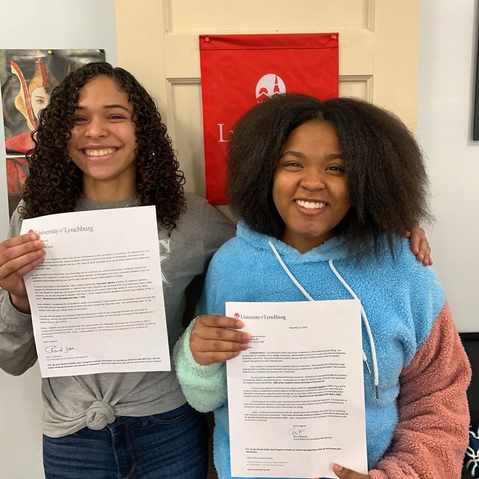Two girls are holding letters and smiling for the camera