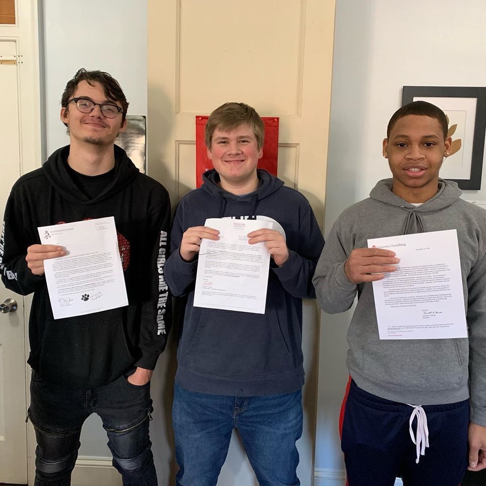 Three young men standing next to each other holding papers
