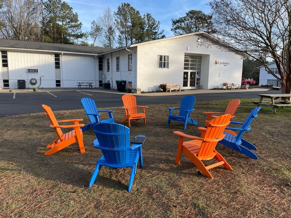 A group of colorful chairs are sitting in a circle in front of a building.