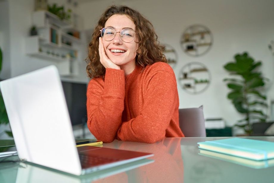 A woman is sitting at a table with a laptop computer.