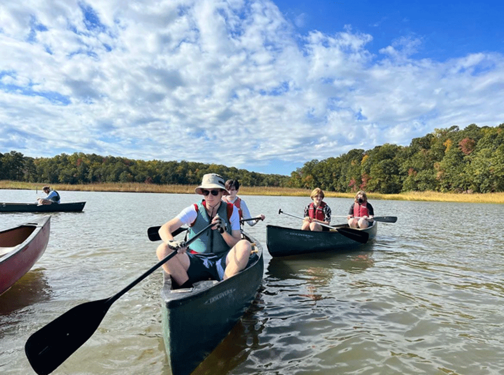 A group of people are paddling canoes on a lake.