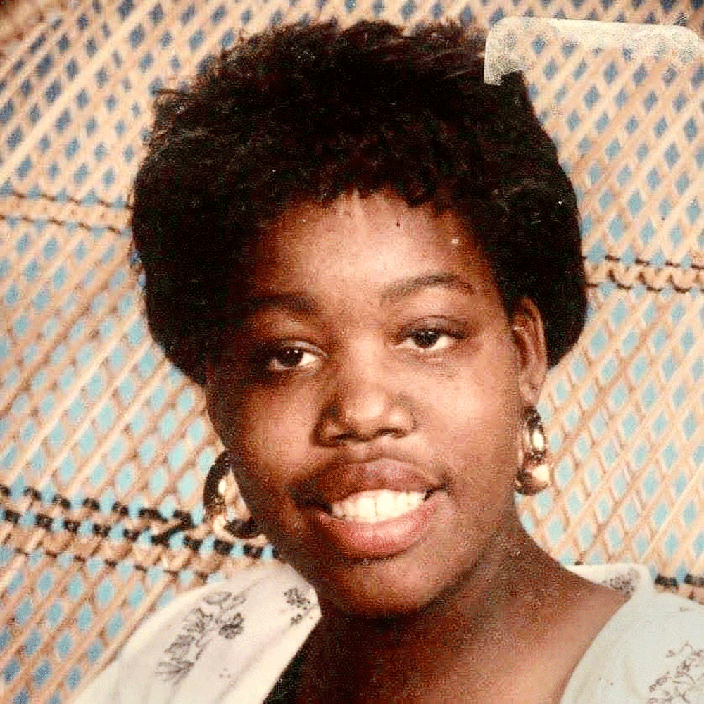 A close up of a woman 's face with a fence in the background.