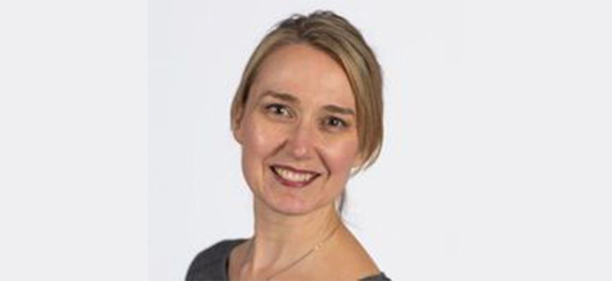A woman is smiling for the camera in front of a white background.
