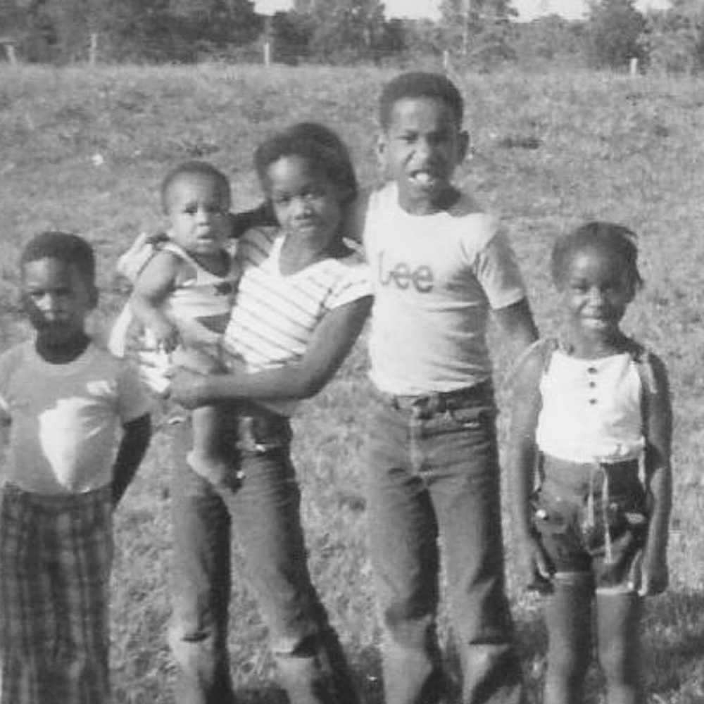 A black and white photo of a group of children standing in a field.