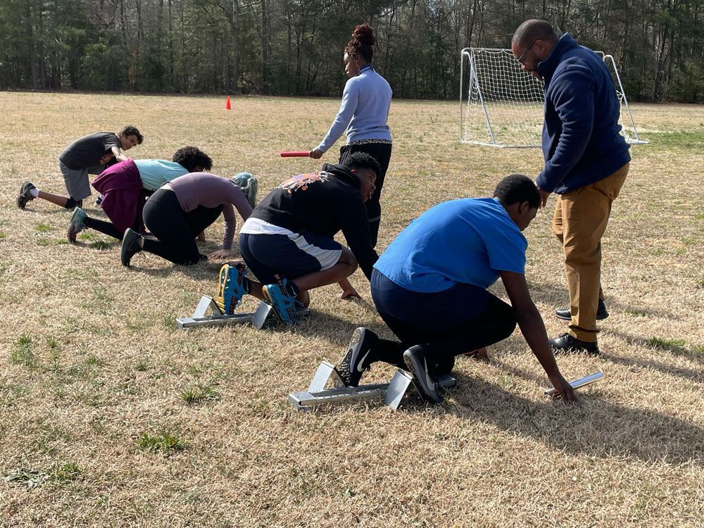 A man is taking a picture of a woman sitting on a stool.