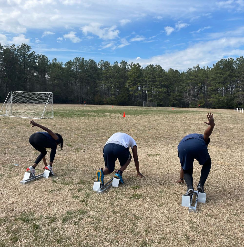 Three people are getting ready to run on a field