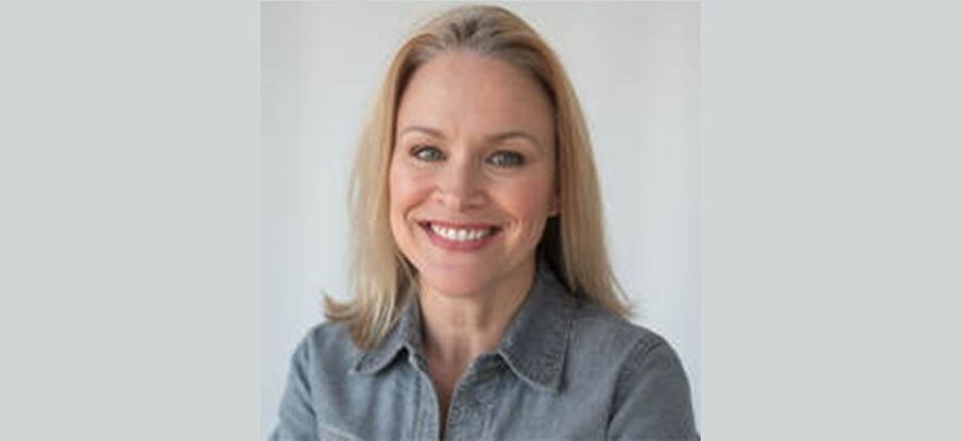 A woman in a blue shirt is smiling for the camera.