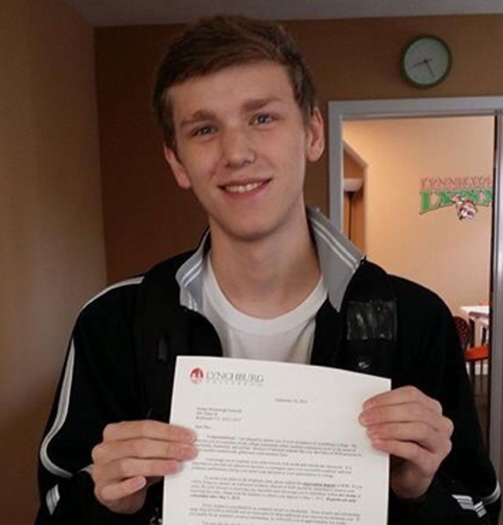 A young man in a black jacket is holding a letter