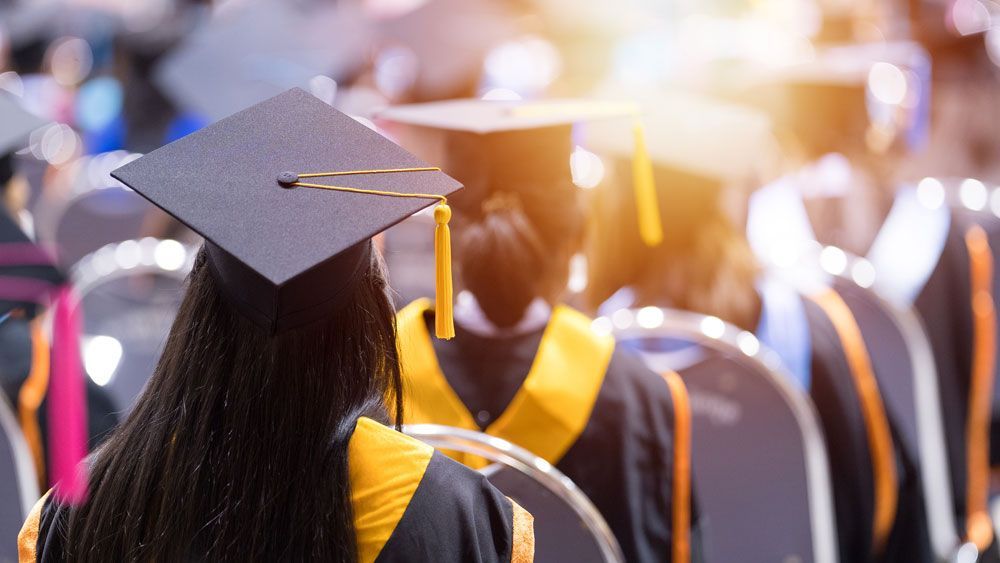 A group of graduates are sitting in chairs at a graduation ceremony.