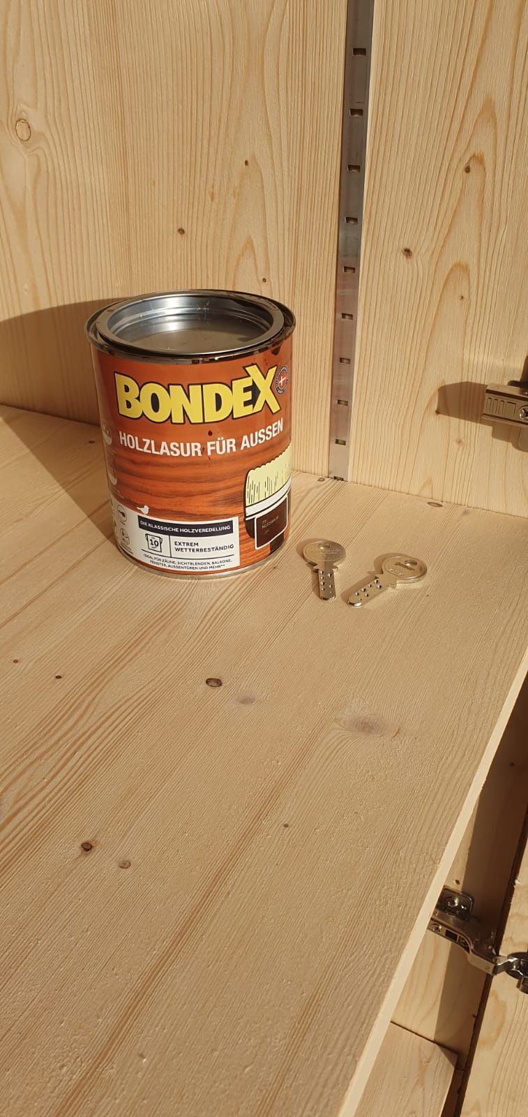 Eine Dose Bondex steht neben zwei Schlüsseln auf einem Holzregal.