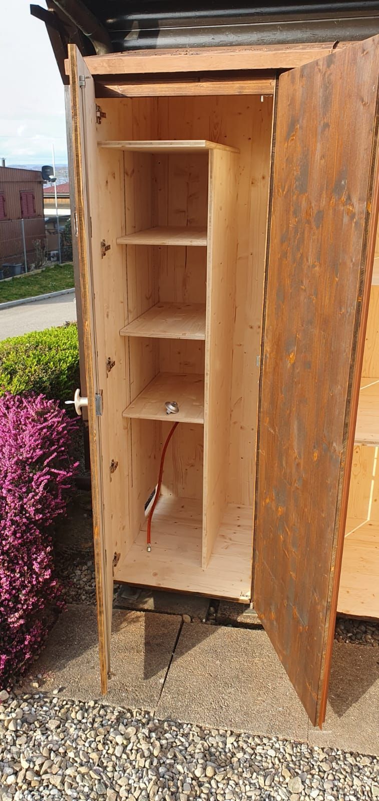 Ein Holzschrank mit offenen Türen und Regalen darin.