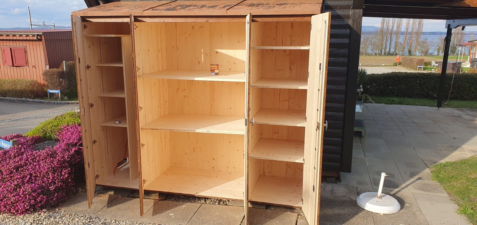 Auf dem Boden steht ein grosser Holzschrank mit geöffneten Türen.