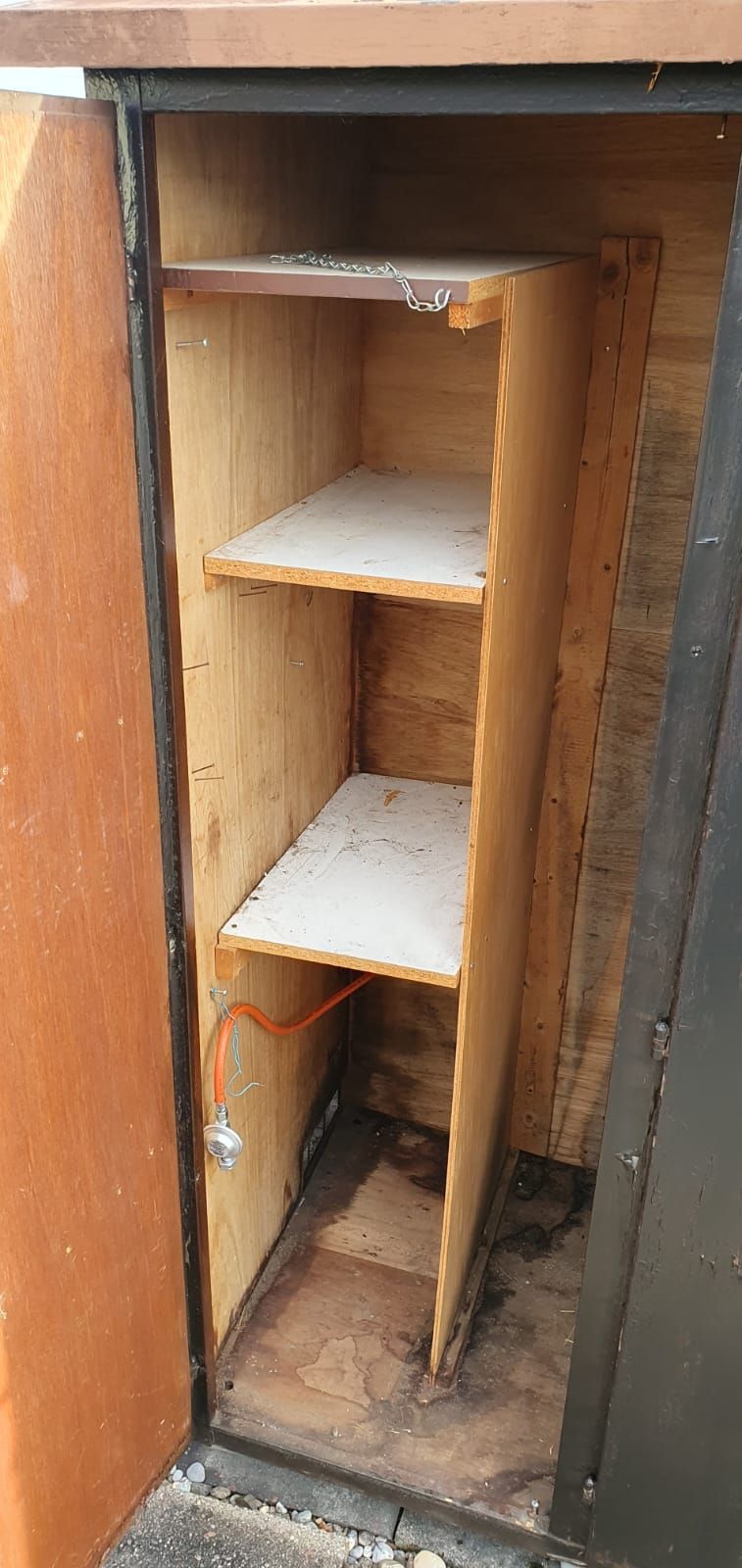 Das Innere eines Holzschranks mit Regalen und einer Tür.