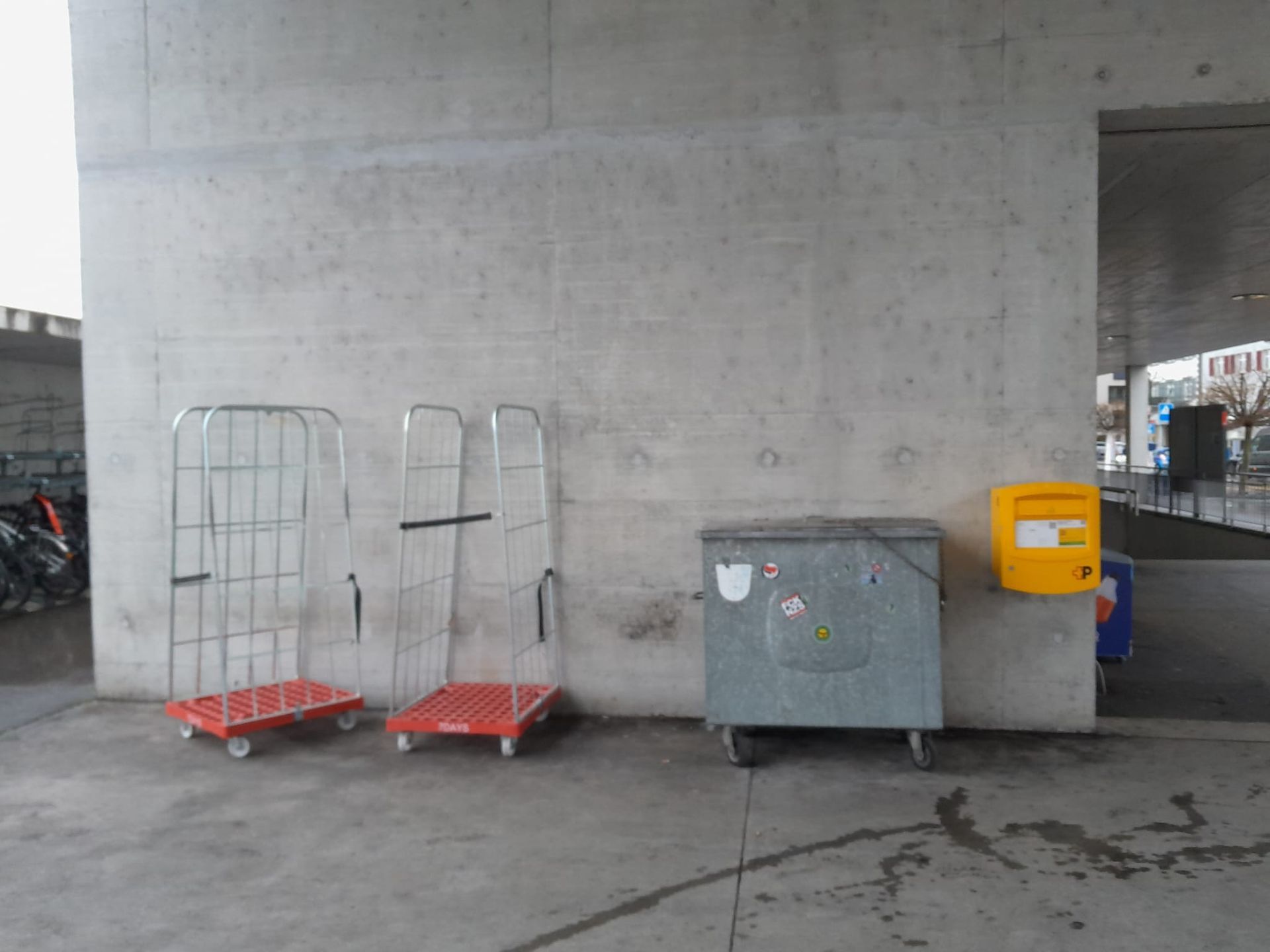 Ein gelber Briefkasten steht neben einem Mülleimer