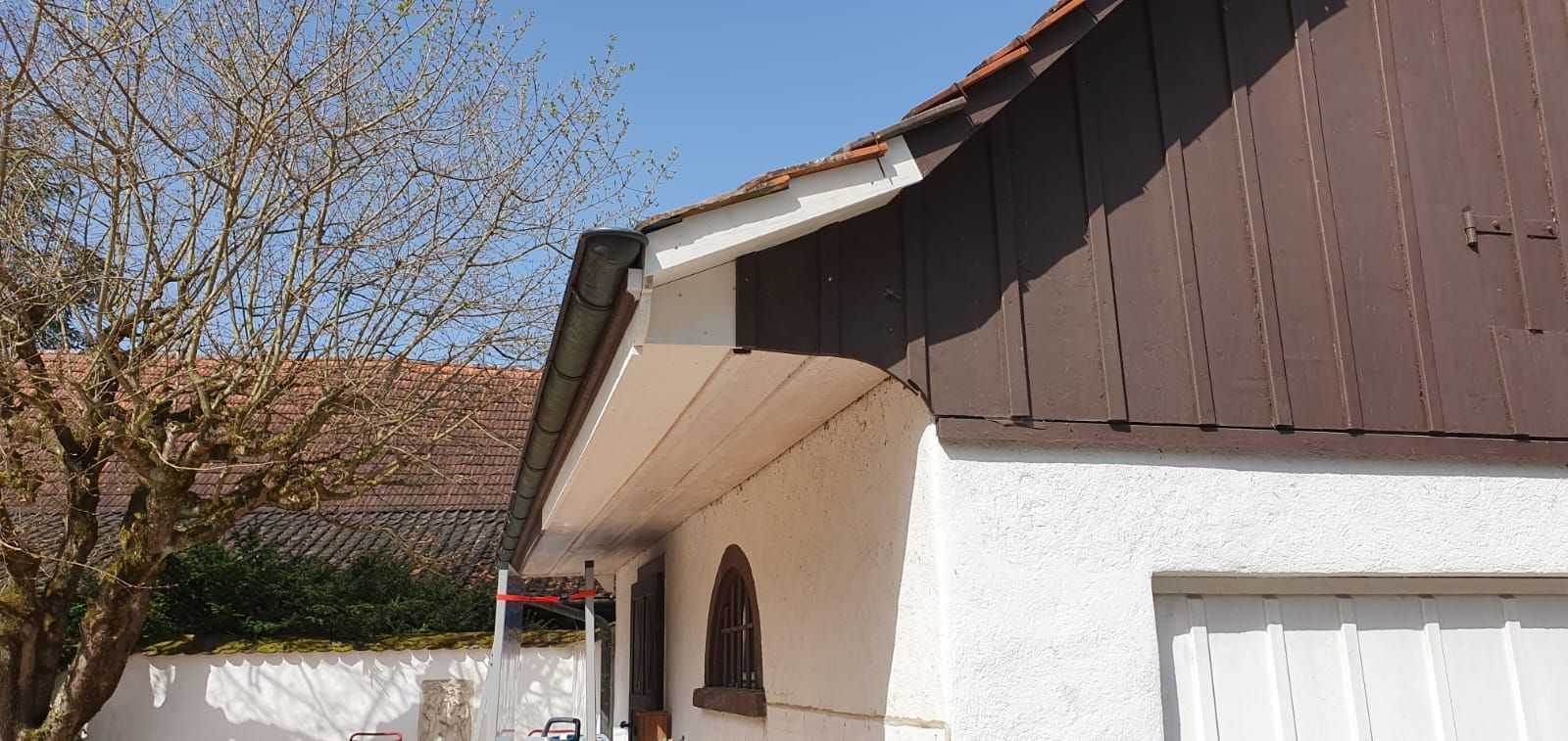 Ein weißes Haus mit einem braunen Dach und einem Garagentor.