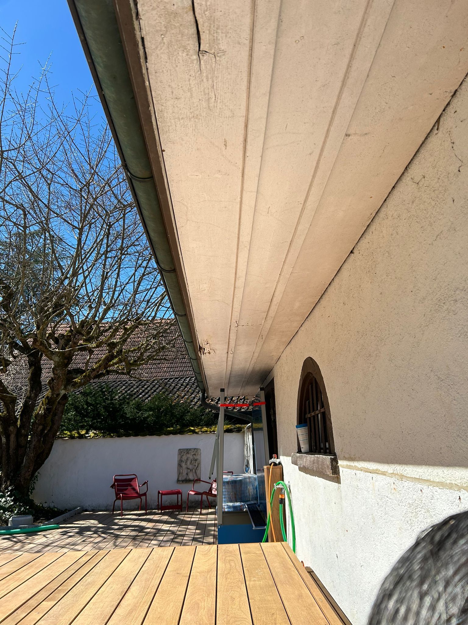 Eine Person sitzt an einem Holztisch vor einem Gebäude.