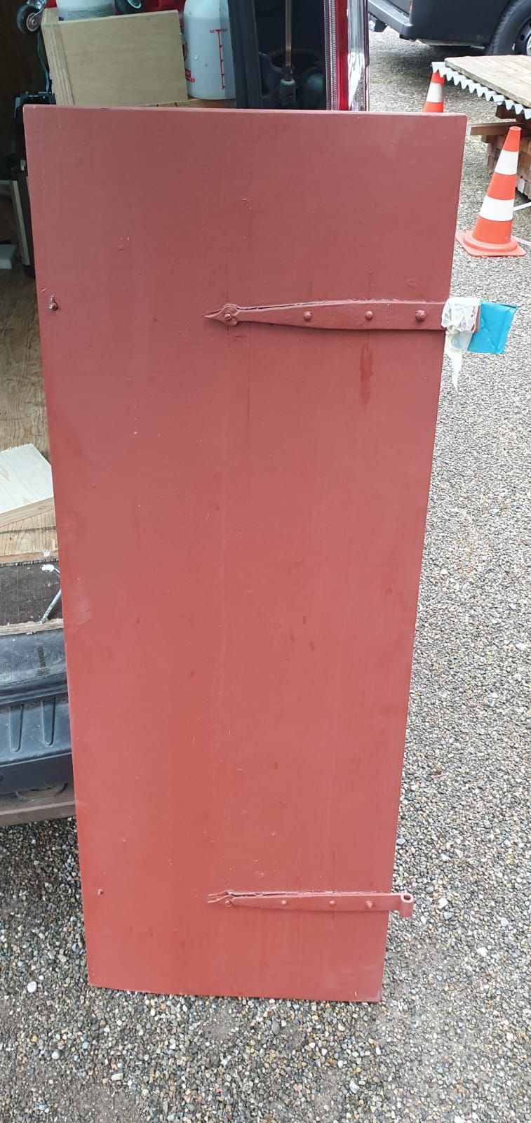 Eine rote Tür liegt neben einem Auto auf dem Boden.