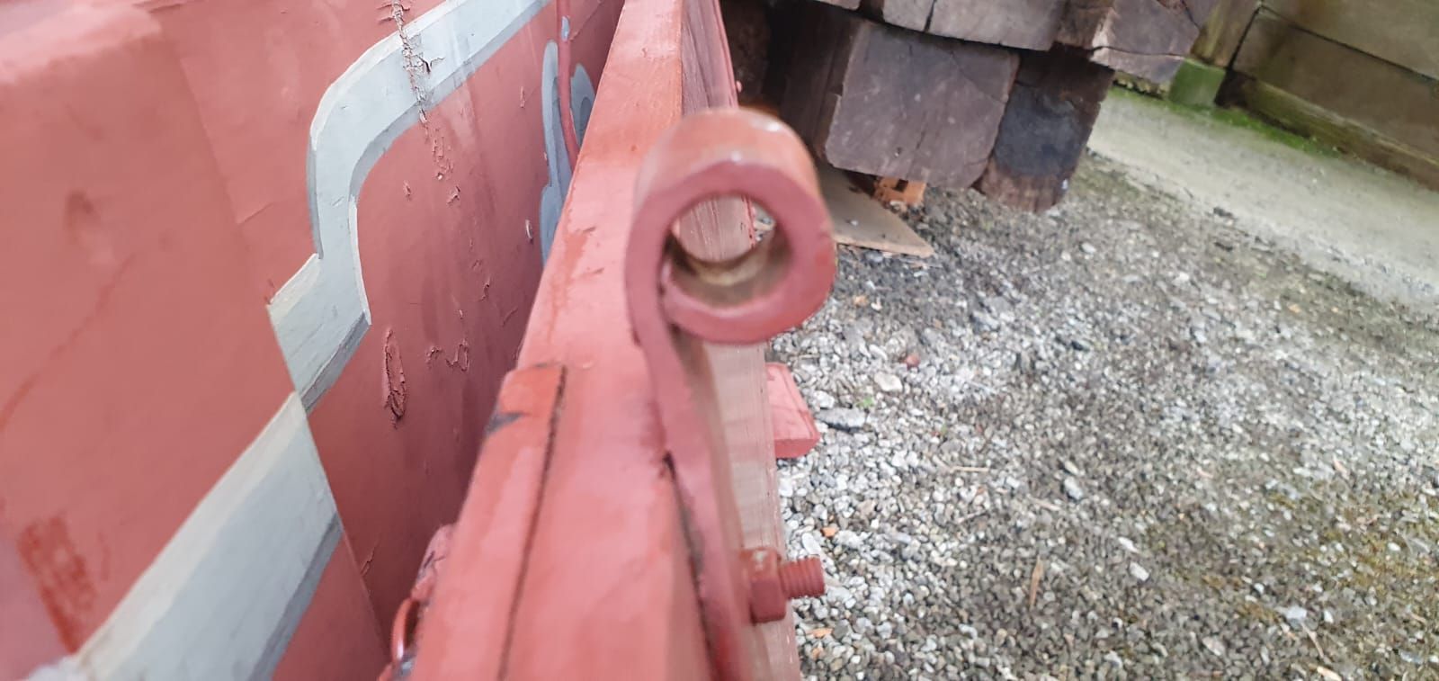 Eine Nahaufnahme eines roten Metallobjekts auf einer Schotterstrasse.