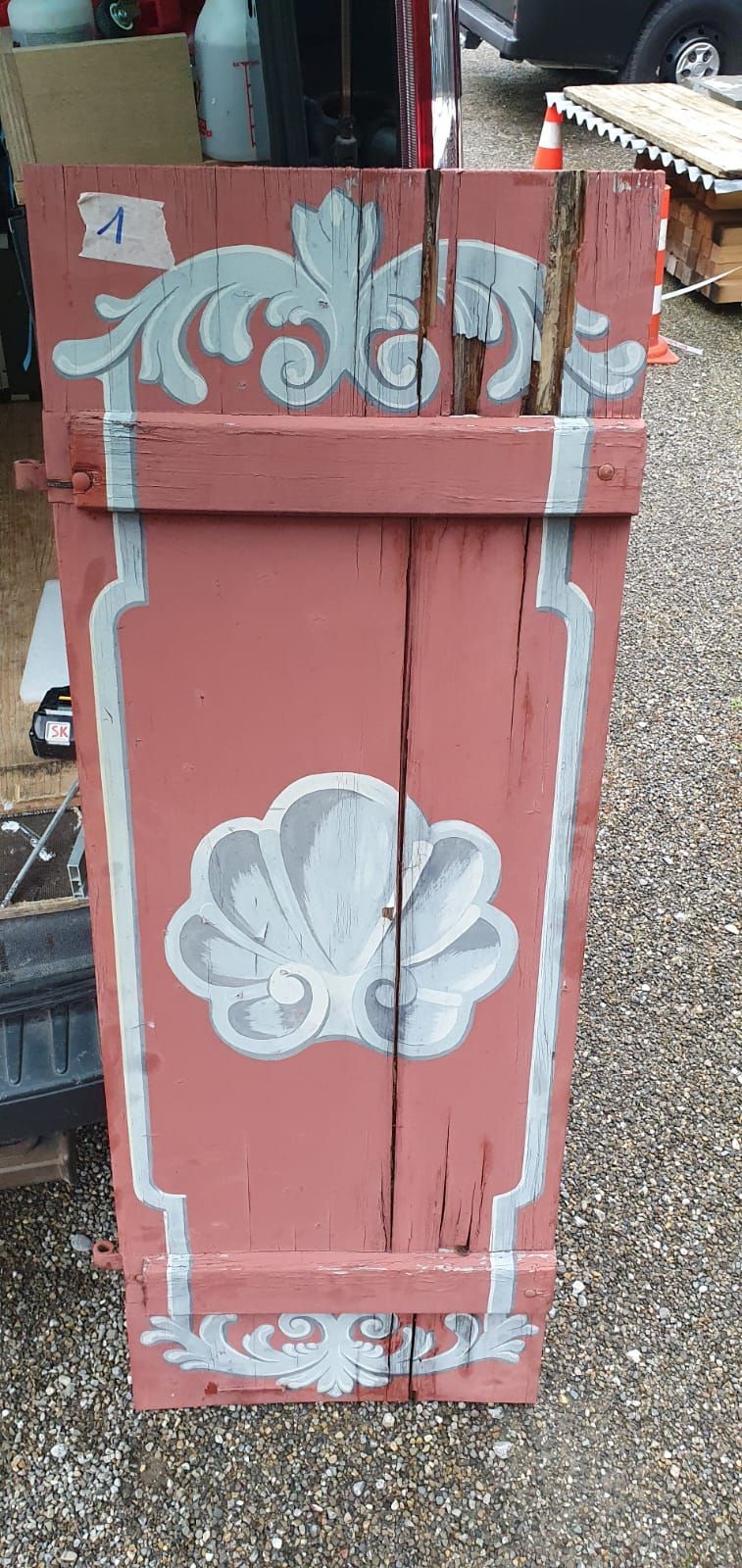 Auf dem Boden steht eine rote Fensterladen mit einem weissen Muster.