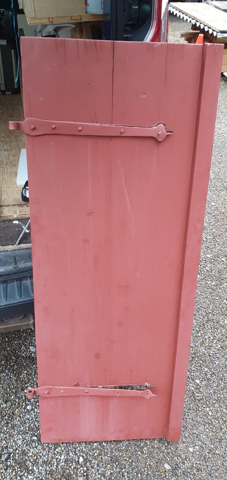 Auf einer Schotterstrasse steht ein roter Fensterladen.