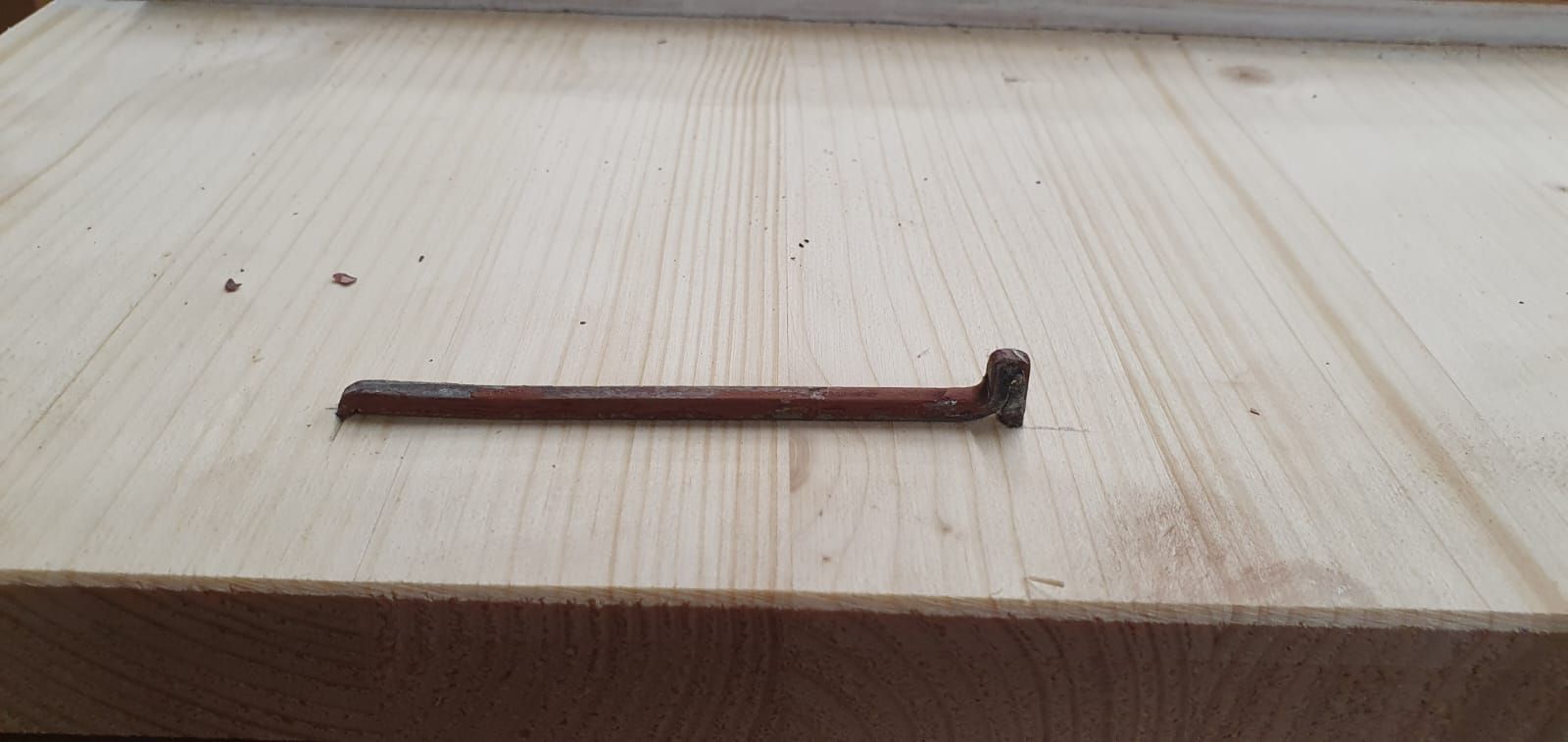 Auf einem Fensterladen liegt ein Nagel.