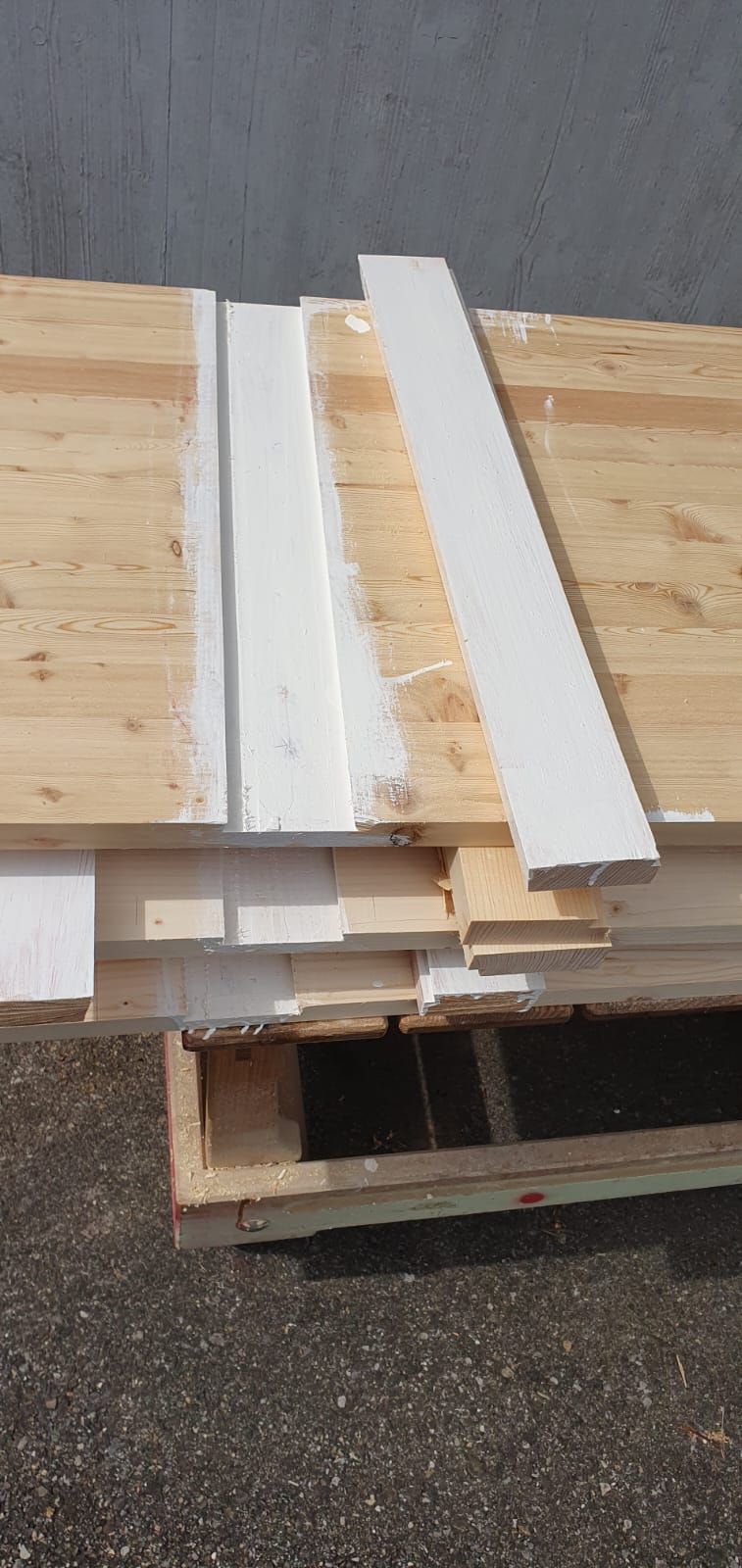 Eine Holzpalette gefüllt mit Holzbrettern und weißen Zierleisten.