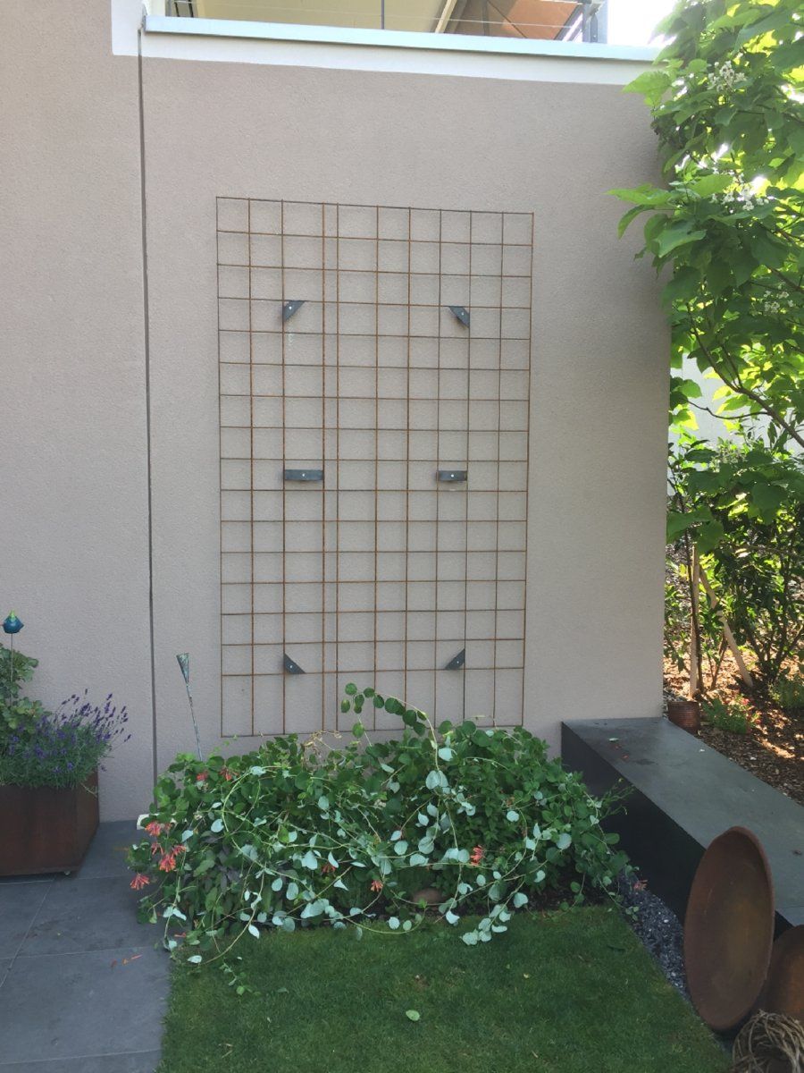 Ein Garten mit einem Spalier an der Seite eines Gebäudes