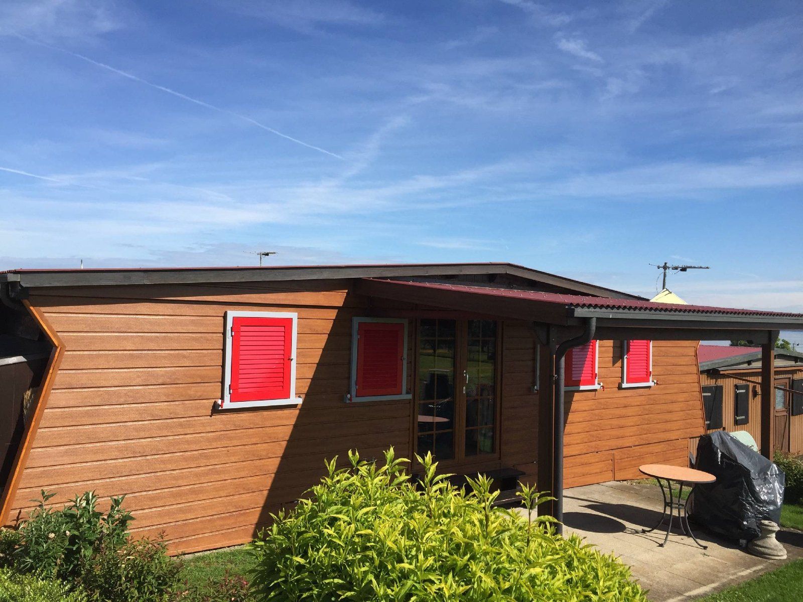 Ein kleines Holzhaus mit roten Fensterläden
