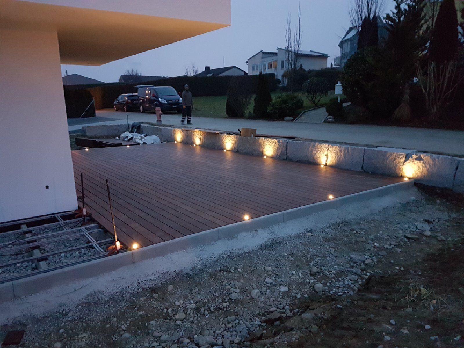 Ein Holzdeck mit Lichtern darauf vor einem Haus