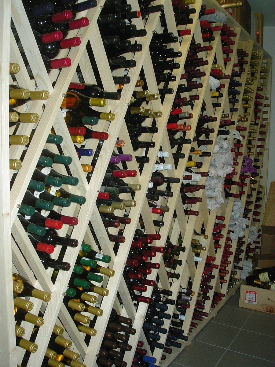 Viele Flaschen Wein liegen aufgereiht auf Holzregalen, Weingestell, Weinlagerung